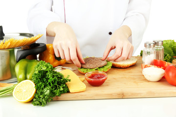 Female hands preparing cheeseburger, isolated on white