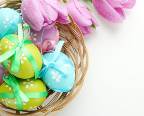 Bright easter eggs in basket and tulips, isolated on white
