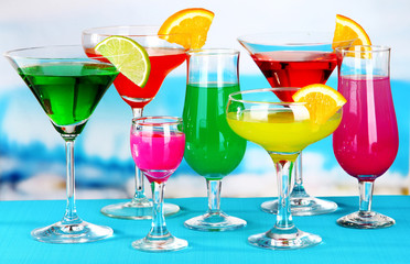 Glasses of cocktails on table near pool