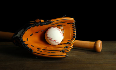 Baseball glove, bat and ball on dark background