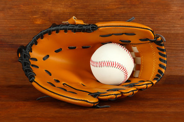 Baseball glove and ball on wooden background