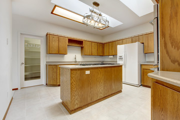 Wood kitchen with island without windows with bright light.