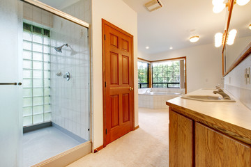 Large white bathroom with tub, shower and wood cabinet.