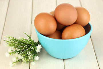 Eggs in blue bowl on wooden table close-up
