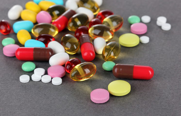 Assortment of pills, tablets and capsules on grey background