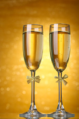 Two glasses of champagne on bright background with lights
