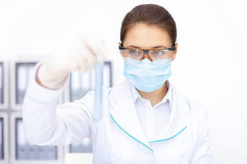 female researcher observing liquid in flask