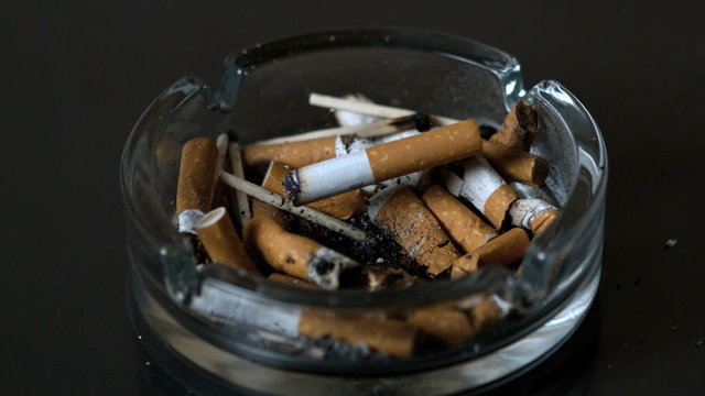 Cigarette falling into ashtray