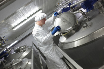 worker in apron and cap, controlling industrial process