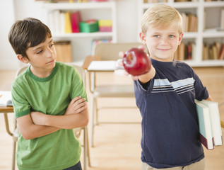 Boy in classroom holding out apple