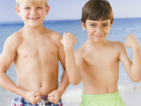 Boys on beach flexing biceps muscles