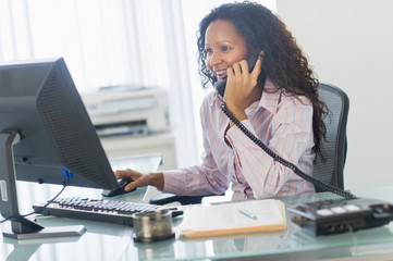 Hispanic businesswoman talking on telephone at desk