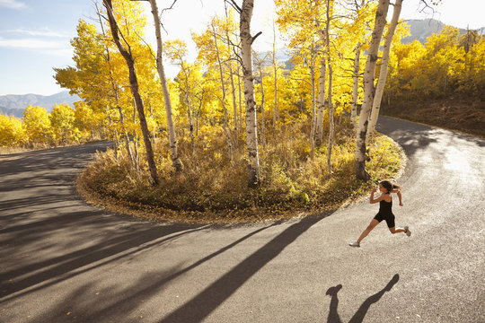 Caucasian woman running along autumn road