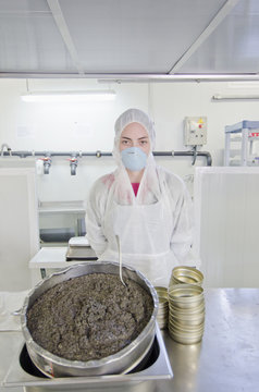 Hispanic worker filling tins with caviar