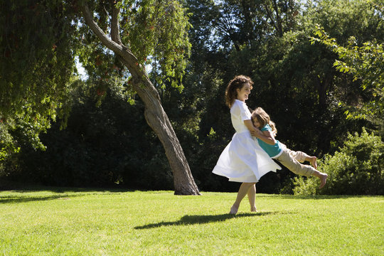 Mother swinging daughter in park