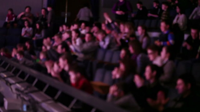 Defocused people applaud at theatre.