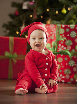 Caucasian baby boy sitting near Christmas tree