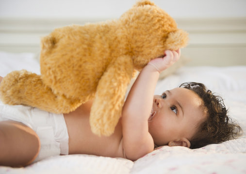 Mixed race baby holding teddy bear