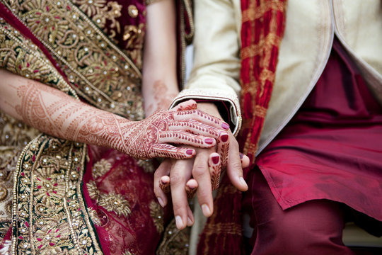 Bride and groom in traditional Indian wedding clothing with henna tattoos