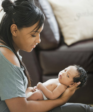 Mixed race mother holding newborn baby