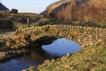 Fototapeta na wymiar Stone Packhorse Bridge. The stone packhorse bridge crossing Watendlath Beck is situated in Watendlath, Cumbria above Derwentwater in the English Lake District.