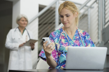 Caucasian nurse using cell phone and laptop