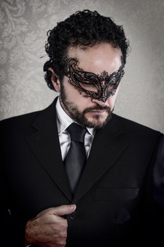 seductive elegant businessman with Venetian mask and black suit