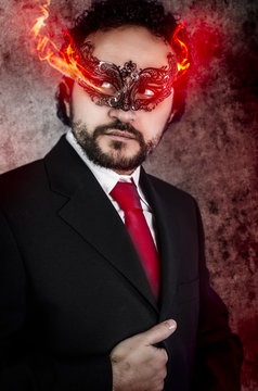 concept evil man with fiery eyes and Venetian mask wearing black