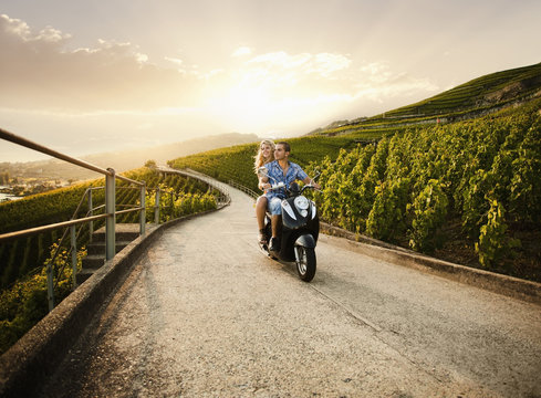 Couple riding scooter in vineyard