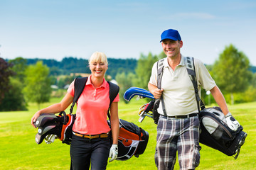 Fototapeta premium Young sportive couple playing golf on a course