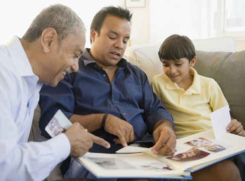 Hispanic grandfather, father and son looking at photo album