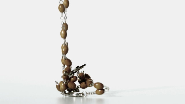Rosary beads falling onto a white surface