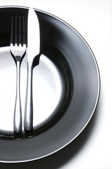steel fork and knife on a black ceramic plate