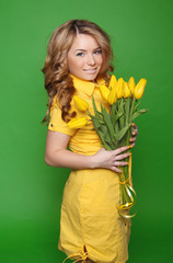 Happy smiling girl with spring-flowering yellow tulips isolated