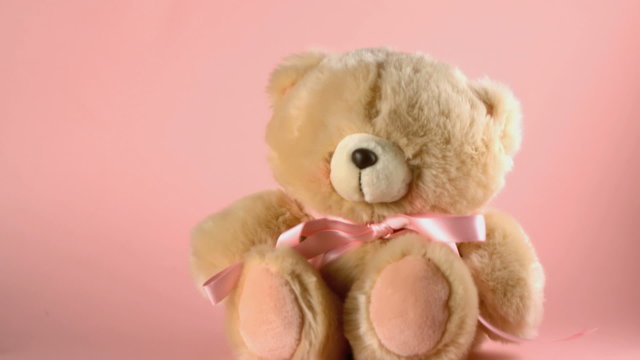 Teddy bear falling and bouncing on a pink surface