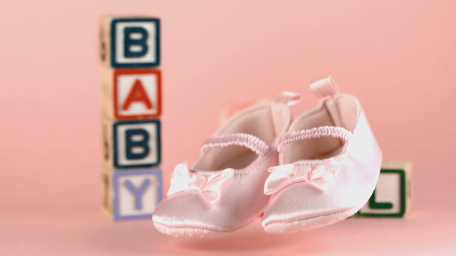Baby shoes falling in front of baby blocks and soother