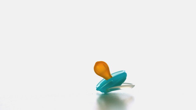 Blue soother falling and bouncing on a white surface