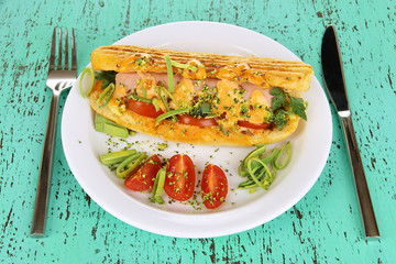 Delicious hot dog on plate on wooden table close-up