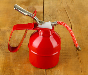 Red oil can, on wooden background