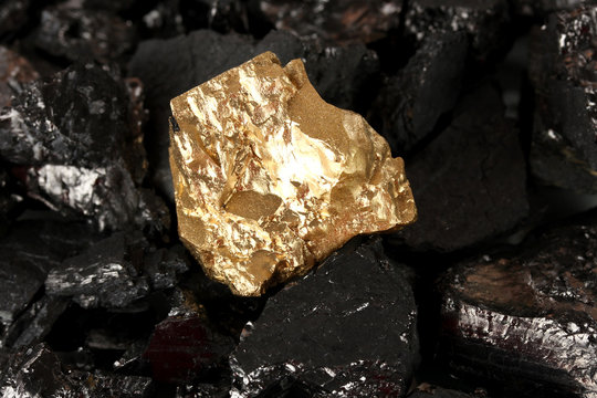 Golden nugget on coals background close-up
