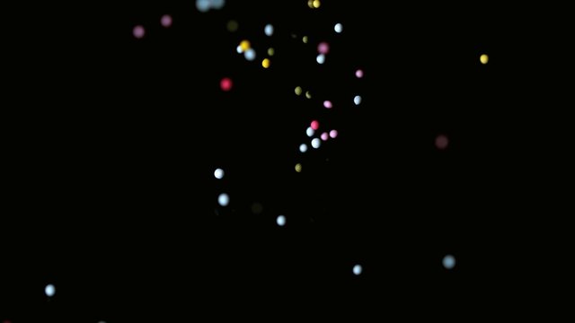 Colourful sprinkles pouring onto black surface