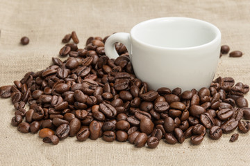 heap of coffee beans on burlap with cup