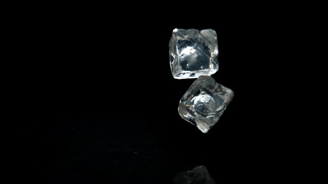 Ice cubes falling and bouncing on black background