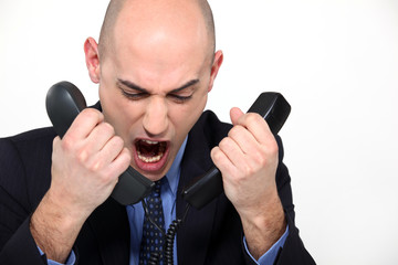 Naklejka premium Bald man shouting into two telephones