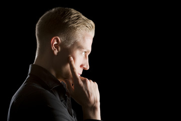 Low key profile portrait of young serious man.