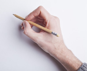 male's hand holding pancil writing on blank white paper
