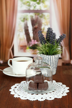 Chocolate sweets under glass cover and hot drink