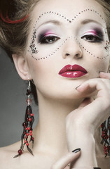 Beautiful girl with a mask and make up on gray background