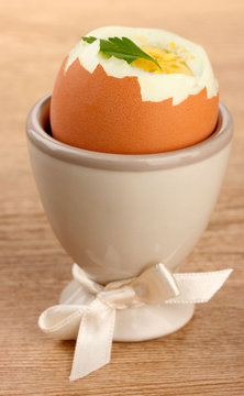 Boiled egg in egg cup, on wooden table