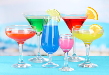 Glasses of cocktails on table near pool
